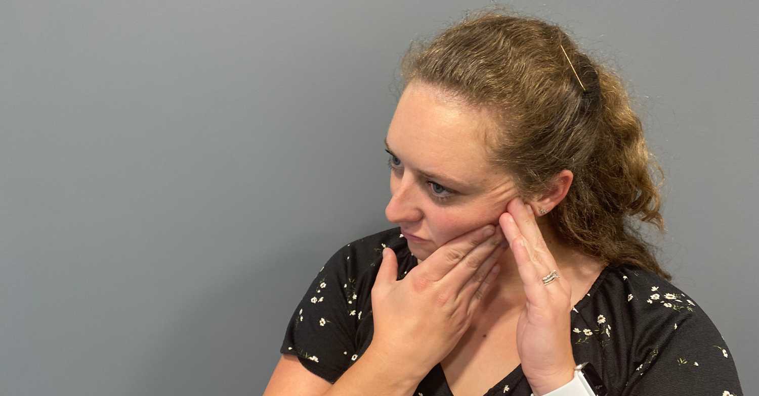 Women holding side of her face with black shirt and brown hair