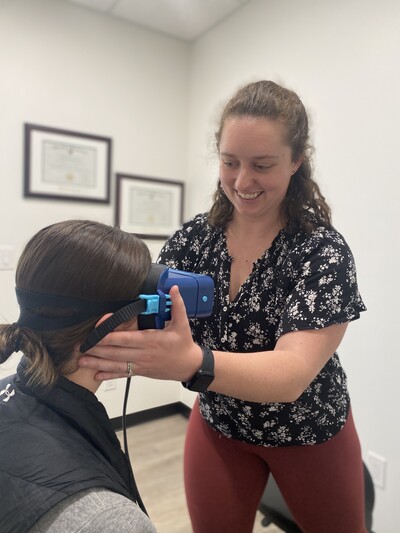 Team member of Nova Physiotherapy in Warman delivering vestibular therapy for dizziness on client. Blue google like equipment is used on the clients head.