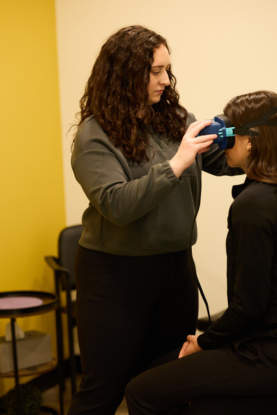 Team member of Nova Physiotherapy in Warman delivering vestibular therapy for dizziness on client. Blue google like equipment is used on the clients head.