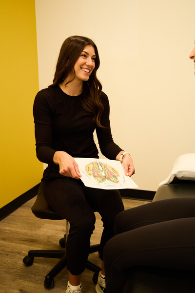 Nova team member and physiotherapist holding pelvic health diagram to provide education to a client on pelvic health care