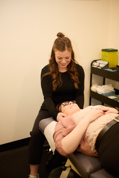Nova team member and chiropractor providing hands on care for women on treatment bed