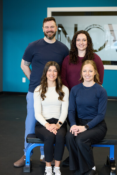 3 women and 1 man all Nova team members and physiotherapists sitting on bench in gym clinic setting