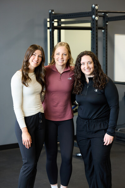 3 women who are team members and physiotherapist standing together in clinic gym