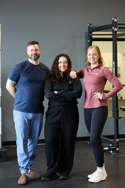 2 women and 1 man who are all team member and physiotherapists standing in clinic gym