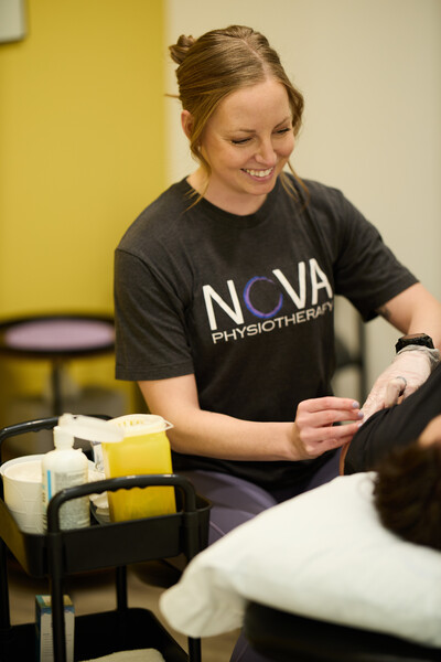 Dry needling treatment provided by physiotherapist wearing grey nova shirt while holding dry needle and other hand gloved