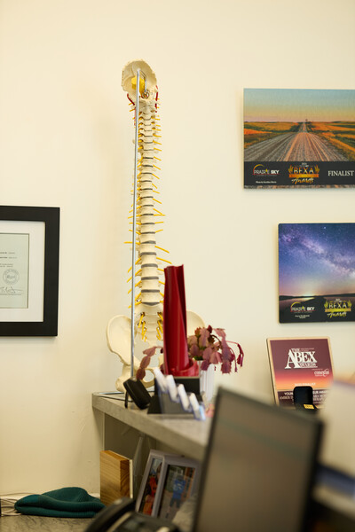 clinic reception area showing computer, spine model, red award and pictures on white wall